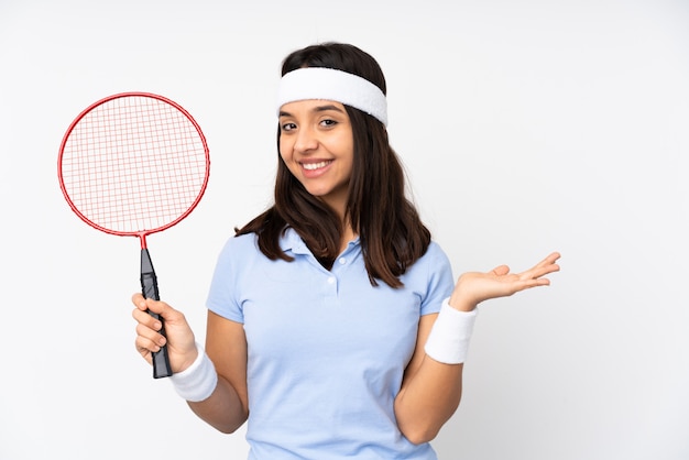 Mulher jovem jogador de badminton sobre parede branca, apresentando uma idéia enquanto olha sorrindo para