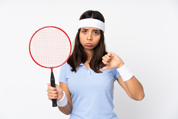 Mulher jovem jogador de badminton sobre parede branca, mostrando o polegar para baixo com expressão negativa