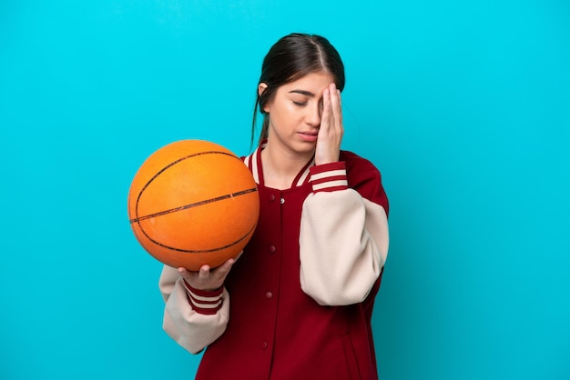 Mulher jovem jogador de basquete caucasiano isolada em fundo azul com dor de cabeça