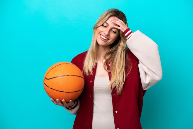 Mulher jovem jogador de basquete caucasiano isolada em fundo azul rindo