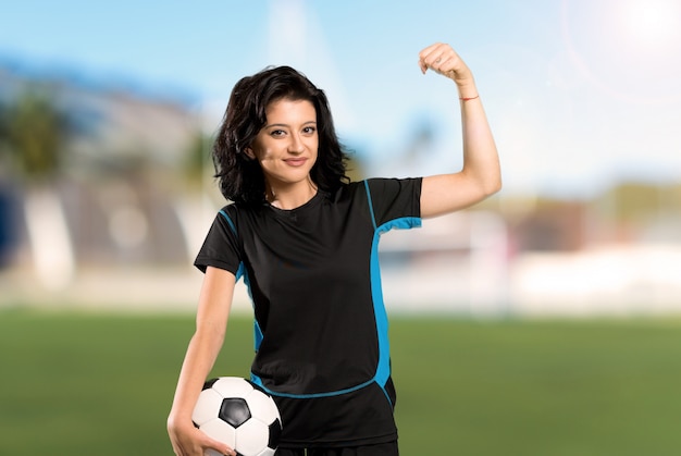 Mulher jovem jogador de futebol comemorando uma vitória ao ar livre