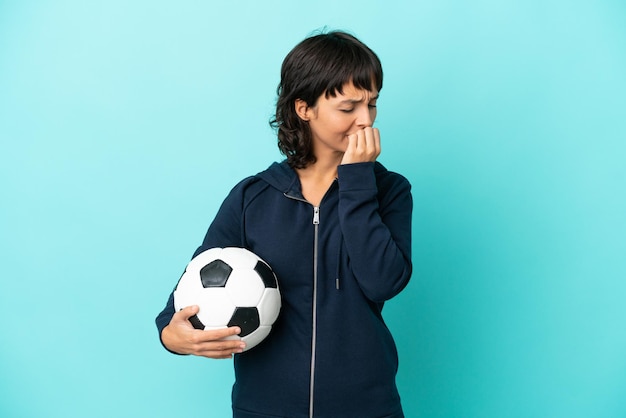 Mulher jovem jogador de futebol de raça mista isolada em fundo azul com dúvidas