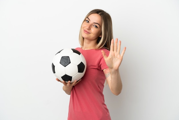 Mulher jovem jogador de futebol em uma parede branca isolada contando cinco com os dedos
