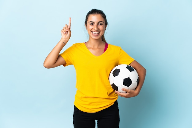 Mulher jovem jogador de futebol hispânico isolado em um fundo azul apontando uma ótima ideia