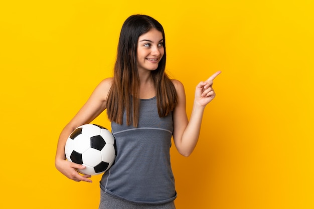 Mulher jovem jogador de futebol isolada em amarelo apontando para cima uma ótima idéia