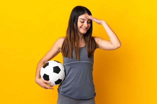 Mulher jovem jogador de futebol isolada em amarelo sorrindo muito