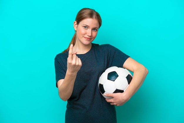 Mulher jovem jogador de futebol isolada em fundo azul fazendo gesto de vinda