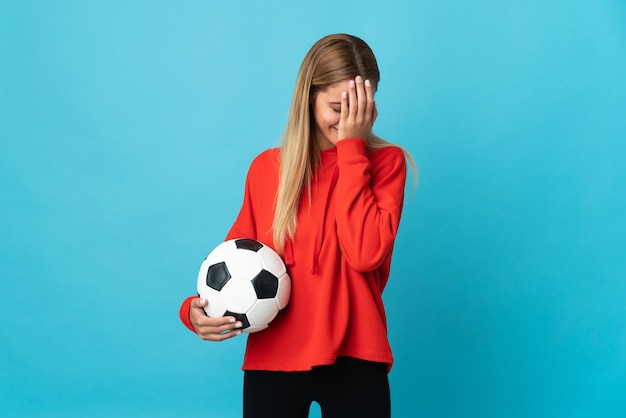 Mulher jovem jogador de futebol isolada na parede azul com expressão cansada e doente