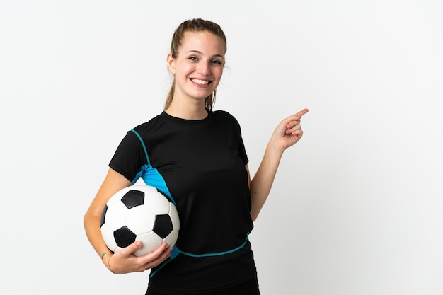 Mulher jovem jogador de futebol isolada na parede branca apontando o dedo para o lado