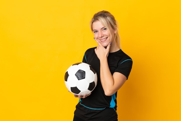 Mulher jovem jogador de futebol russo isolada em fundo amarelo feliz e sorridente