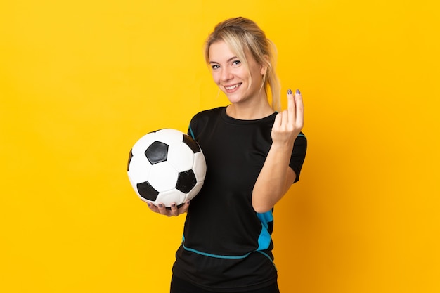 Mulher jovem jogador de futebol russo isolada na parede amarela fazendo gesto de dinheiro