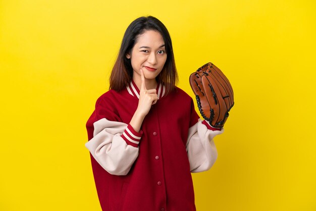 Mulher jovem jogador vietnamita com luva de beisebol isolada em fundo amarelo tendo dúvidas e pensando
