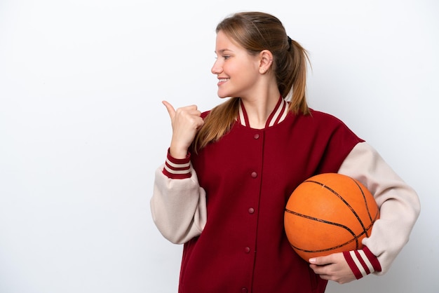 Mulher jovem jogadora de basquete isolada no fundo branco, apontando para o lado para apresentar um produto