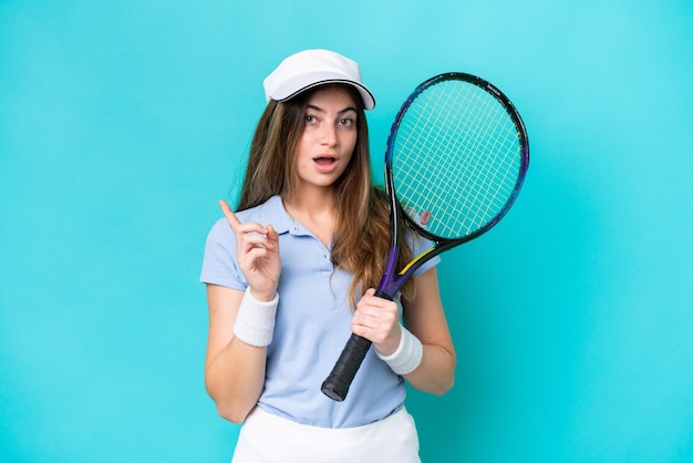 Mulher jovem jogadora de tênis isolada em fundo azul com a intenção de perceber a solução enquanto levanta um dedo