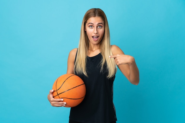 Mulher jovem jogando basquete branco com expressão facial surpresa