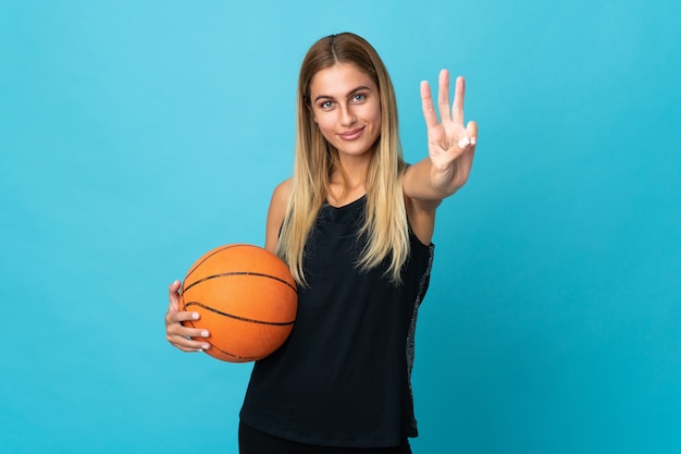 Mulher jovem jogando basquete branco feliz e contando três com os dedos