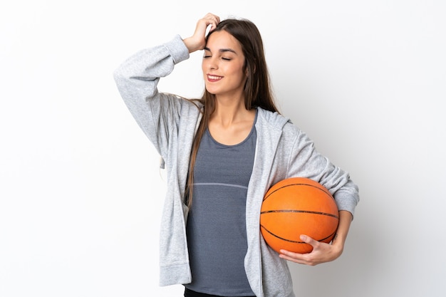 Mulher jovem jogando basquete isolada em uma parede branca e sorrindo muito