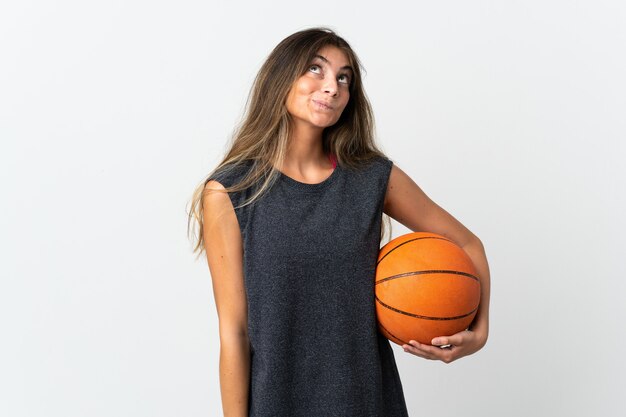 Mulher jovem jogando basquete isolada no fundo branco e olhando para cima