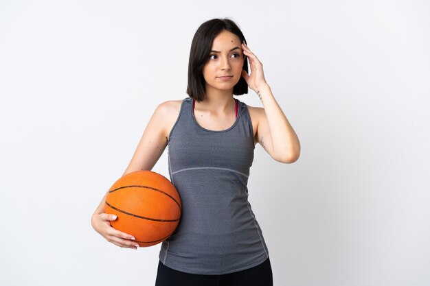 Mulher jovem jogando basquete, isolada no fundo branco, tendo dúvidas e pensando