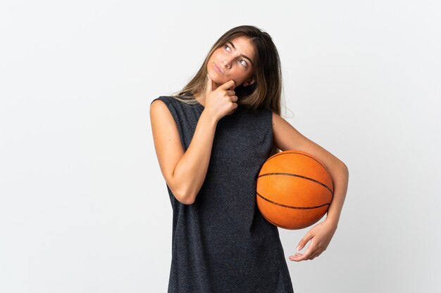 Mulher jovem jogando basquete isolado no branco, tendo dúvidas