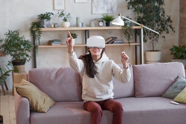 Foto mulher jovem jogando videogame realista com óculos de realidade virtual em casa