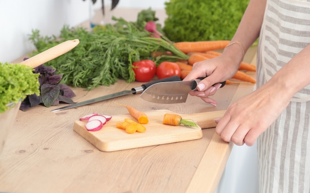 Mulher jovem, legumes cortantes, cozinha