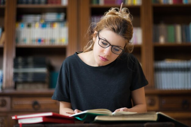 Mulher jovem lendo livros na biblioteca