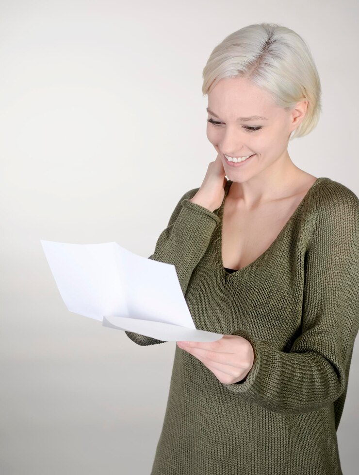 Foto mulher jovem lendo um jornal enquanto está de pé contra um fundo branco