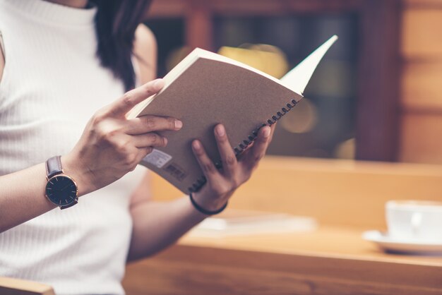 Mulher jovem, lendo um livro, com, xícara café