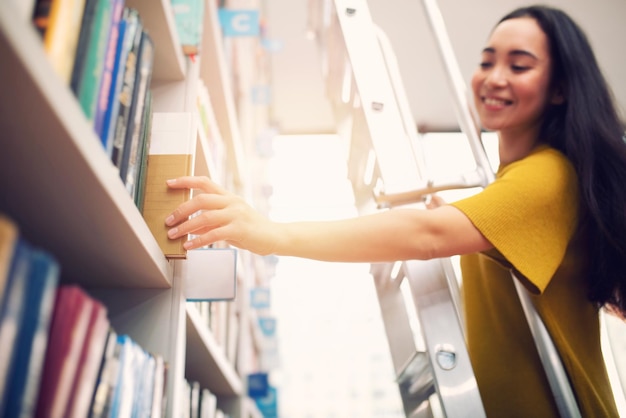 Foto mulher jovem lendo um livro enquanto está de pé na prateleira