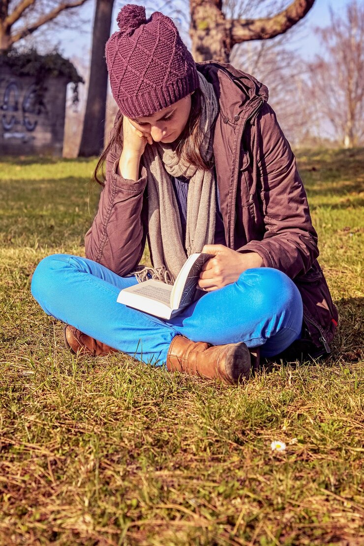 Foto mulher jovem lendo um livro sentada no campo
