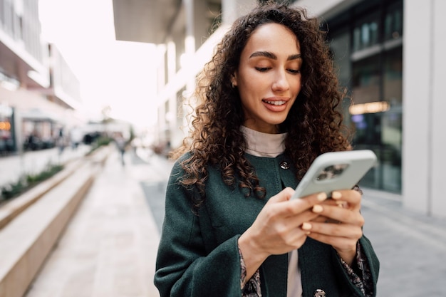 Foto mulher jovem lendo uma mensagem ou usando o telefone na cidade