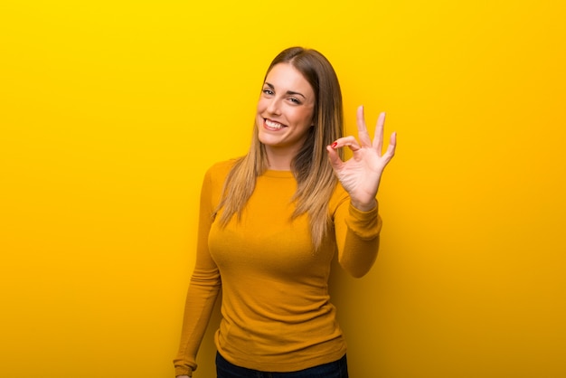 Mulher jovem, ligado, experiência amarela, mostrando, um, tá bom sinal, com, dedos