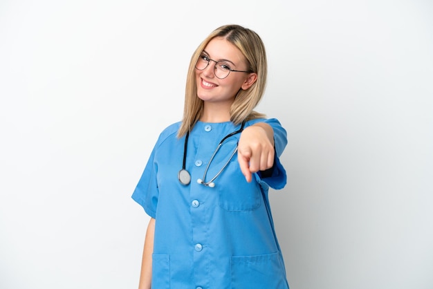 Mulher jovem médica cirurgiã isolada em fundo branco, apontando para a frente com expressão feliz