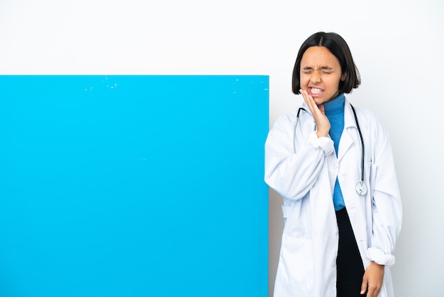Mulher jovem médica de raça mista com um grande cartaz isolado na parede branca com dor de dente