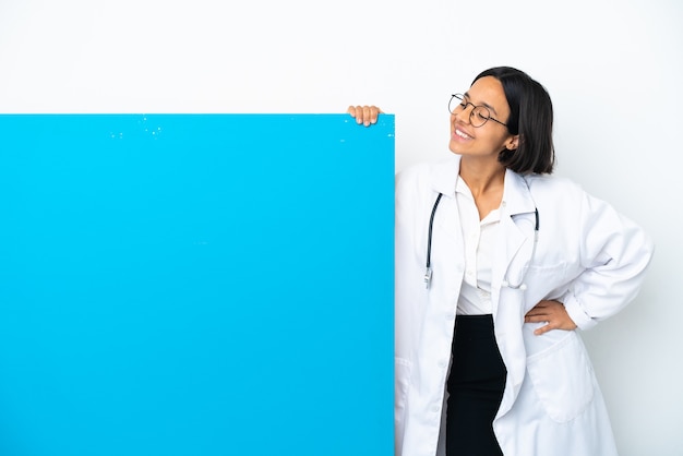 Mulher jovem médica de raça mista com um grande cartaz isolado no fundo branco com os braços cruzados e feliz
