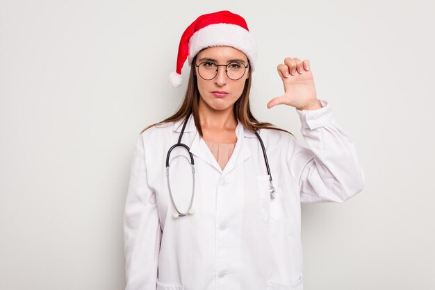 Mulher jovem médico caucasiano usando um chapéu de papai noel isolado no fundo branco