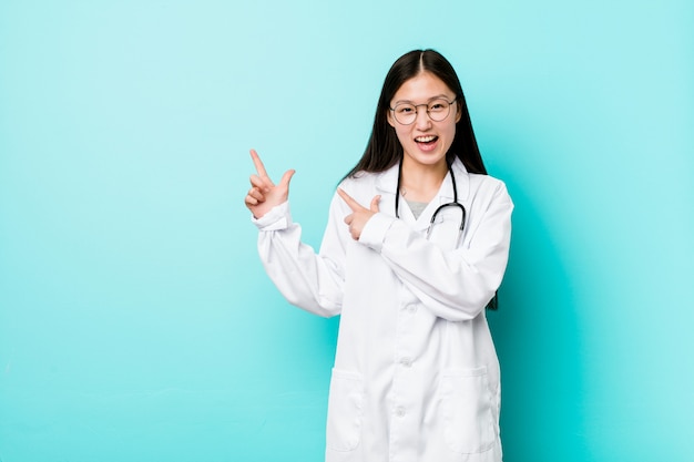 Mulher jovem médico chinês apontando com o dedo indicador para um espaço em branco, expressando emoção e desejo.