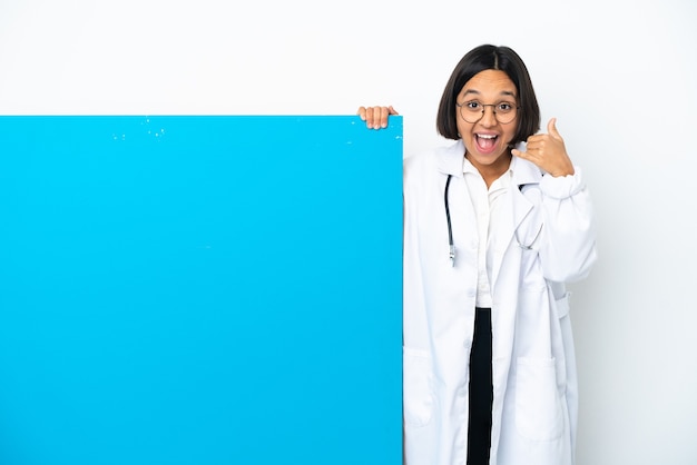 Mulher jovem médico de raça mista com um grande cartaz isolado no fundo branco, fazendo gesto de telefone. ligue-me de volta sinal