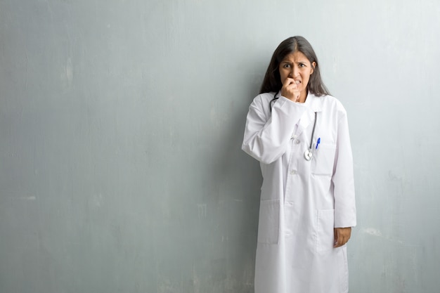 Mulher jovem médico indiano contra um muro roer unhas
