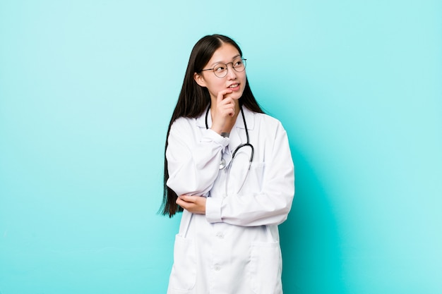 Mulher jovem médico relaxado pensando em algo olhando para um espaço de cópia.