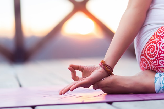 Foto mulher jovem meditando ao ar livre na natureza, pôr do sol, perto das mãos, fazendo ioga mudra