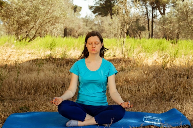 Mulher jovem meditando na floresta, relaxamento, ioga, poses para um estilo de vida saudável