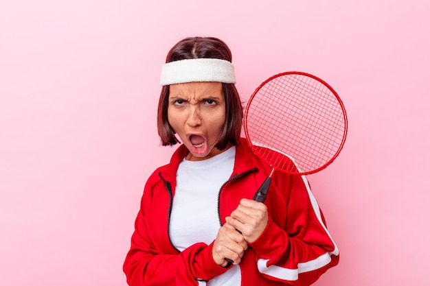 Mulher jovem mestiça jogando badminton isolada na parede rosa