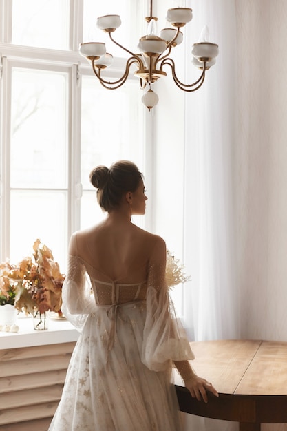 Mulher jovem modelo com um vestido de noiva vintage com as costas nuas, posando no interior do vintage.