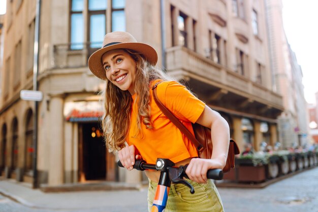 Mulher jovem montando uma scooter elétrica no verão na rua vida ativa conceito ecológico