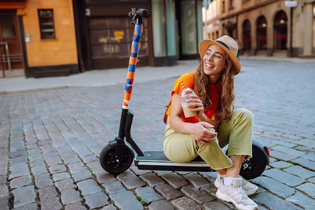 Foto mulher jovem montando uma scooter elétrica no verão na rua vida ativa conceito ecológico