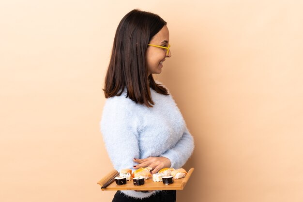 Mulher jovem morena de raça mista segurando sushi