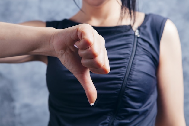 Mulher jovem mostrando o polegar para baixo