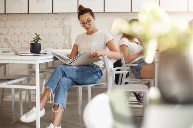 Foto mulher jovem na moda folheando uma revista procurando inspiração em seus trinta anos